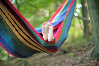 Kinderfüße schauen aus einer buntgestreiften Hängematte hervor