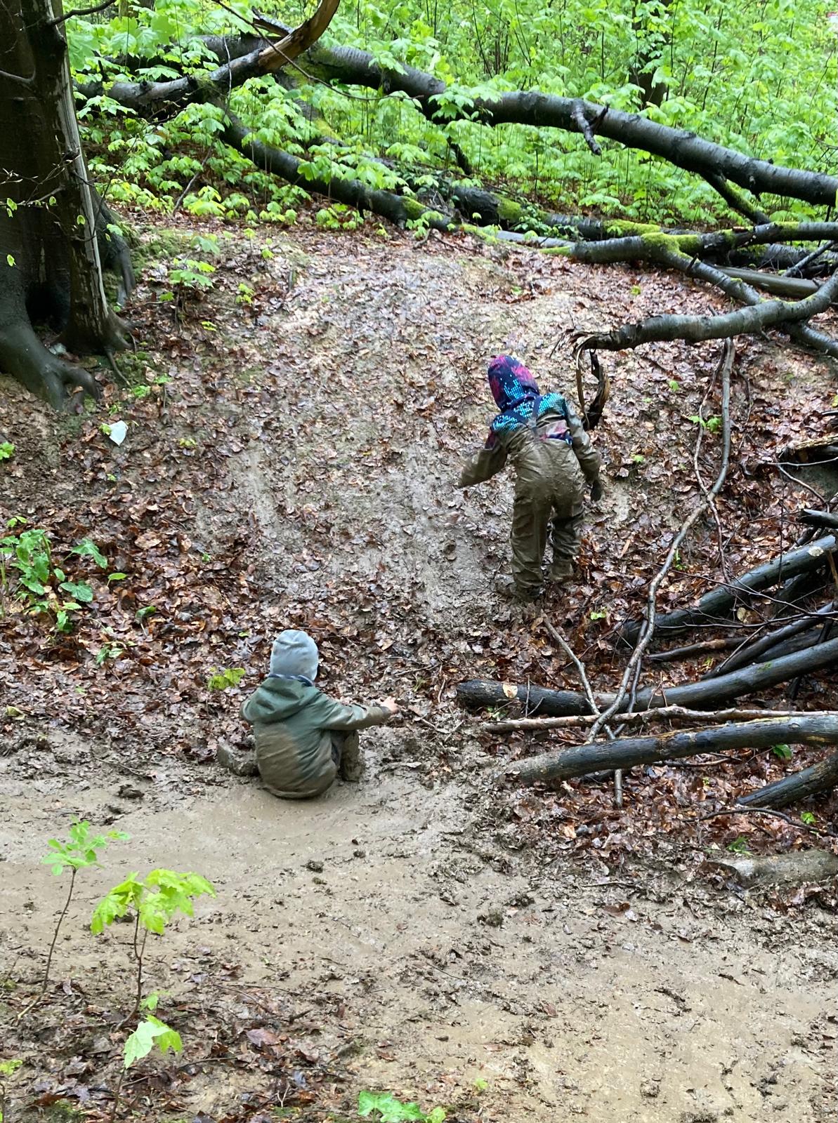 Kinder spielen an einem kleinen Hang im Matsch